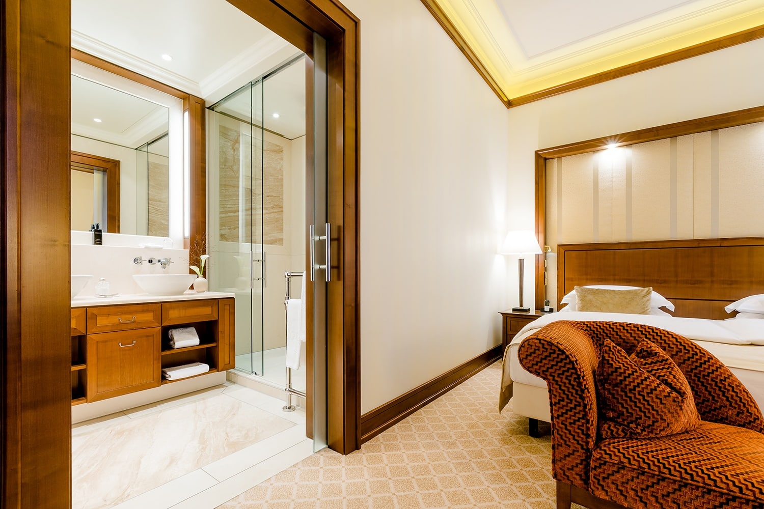Vor dem Doppelbett in der Hotel Suite Köln befindet sich das Badezimmer mit zwei Waschbecken und großer Dusche