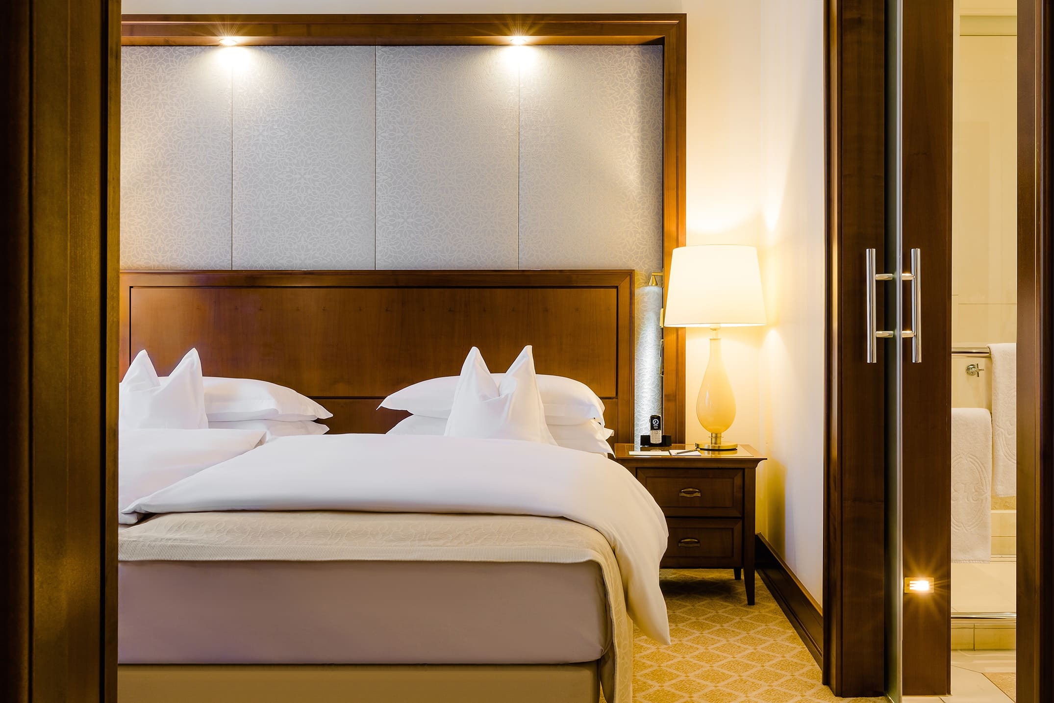 Blick auf die rechte Betthälfte eines Doppelbetts und die daneben stehende Lampe in der Luxus Suite Köln