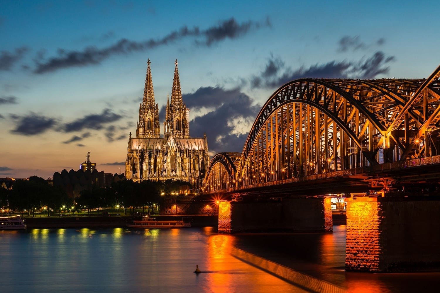 Blick am Abend auf die Hohenzollernbrücke und den beleuchteten Kölner Dom